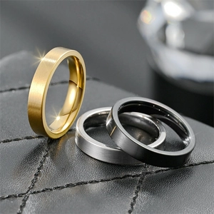Primo piano di anelli in acciaio al titanio opaco da 4mm in oro, argento e nero.