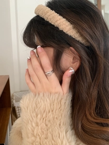 Detail showing plush beige headband with silver ring and pearl earring on a model