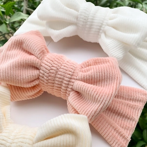 Detailed close-up of three corduroy baby headbands in white, pink and beige tones