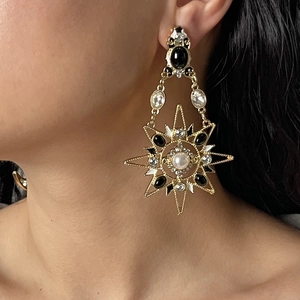 Dettaglio dell'orecchino vintage dorato con pietra nera, perle bianche e strass lucidi