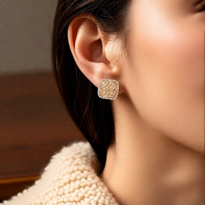 Detailed view of champagne gold square zircon earrings worn on ear for an elegant look