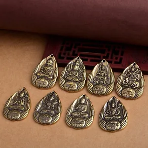 Detail view of eight vintage brass Buddhist guardian deity pendants in teardrop shape