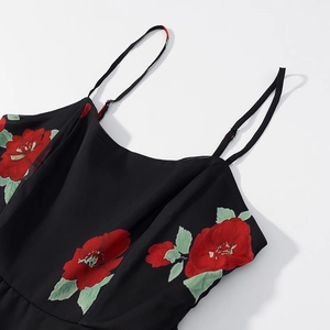 Detail view of adjustable spaghetti straps and red floral print on a black chiffon dress