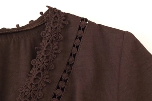 Detail des V-Ausschnitts mit feiner Spitzenstickerei und Stoffstruktur am braunen Kleid