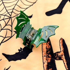 Close-up of green bat shark hair clip with glitter resin and metal spring detail