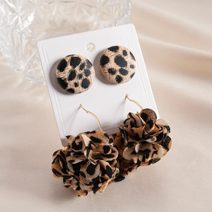 Detail of leopard print fabric flower earrings with gold studs on beige silk background