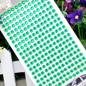 Macro shot of 3mm green round acrylic rhinestones on self-adhesive backing sheet