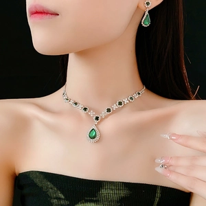Vintage jewelry set with emerald teardrop necklace and matching earrings on a model