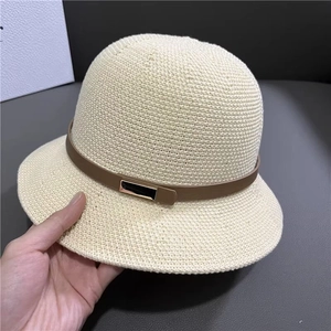Détail de la texture d'un chapeau de soleil beige avec lanière en cuir brun et boucle