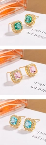 Macro detail of square-cut emerald, pink, and blue zircon earrings in gold frames