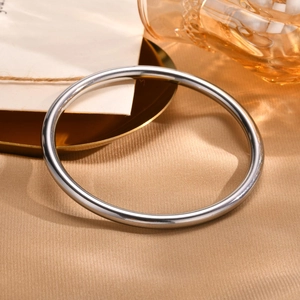 Detailed view of polished stainless steel bangle on elegant silk fabric