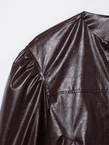 Close-up of pleated shoulder detail and stitched texture on burgundy faux leather jacket