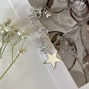 S925 sterling silver star bracelet with chunky chain and bell on a minimalist background