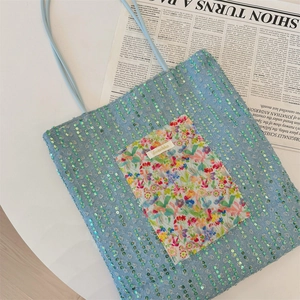 Detail of blue sequined tote bag with floral pocket and delicate shoulder strap
