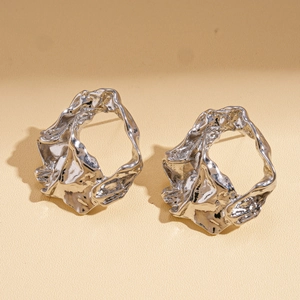 Detailed macro shot of silver earrings with irregular molten metal texture and high gloss