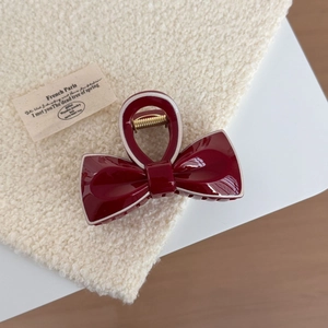 Elegant deep red bow hair claw clip with glossy finish and cream white outline detail