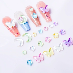 Macro shot of 3D aurora moon and star nail charms on long manicured acrylic nails