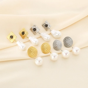 Detail of spiral texture earrings with devil eye charms and baroque pearls on silk