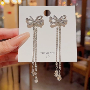 Detail of silver bow earrings with sparkling zircons, long tassels and water drop pendants
