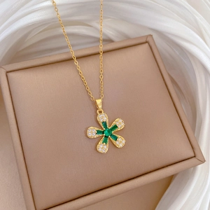 Golden five-petal flower necklace with green gemstone on silk jewelry box display