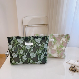 Close-up of floral embroidery on sheer mesh cosmetic bags with a simple wish tag