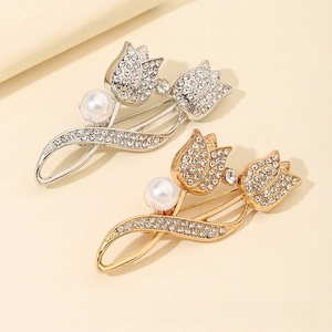 Detailed view of silver and gold tulip brooches with micro-pave zircons and pearls