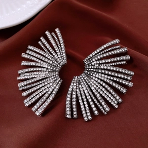 Vue macro de boucles d'oreilles en éventail avec strass sur tissu rouge foncé