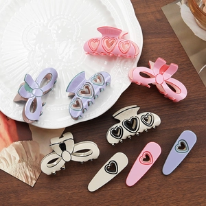 Pink and purple bow hair claw clips set on a ceramic plate over wooden surface