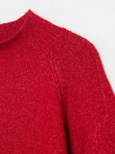 Close-up of red knit sweater featuring a ribbed collar and raglan sleeve stitching