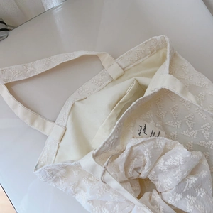 Macro detail of French vintage lace embroidery and canvas inner pocket on tote bag