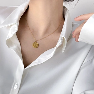 Minimalist gold sun medallion pendant necklace worn on elegant white satin blouse