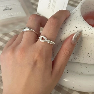 Detail shot of 925 silver knot ring and liquid metal style band on model finger