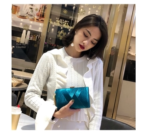 Detail of lake blue pleated satin clutch bag with gold hardware and chain strap