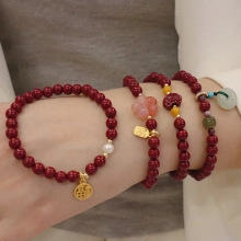 Detail view of red beaded bracelet set with gold Fu pendant and pink flower charms