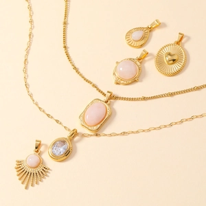 Détail d'un ensemble bijoux en titane doré avec pierres roses et pendentifs cœur