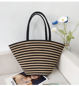 Detail view of woven cotton rope shoulder bag in black and beige stripes on a beige sofa