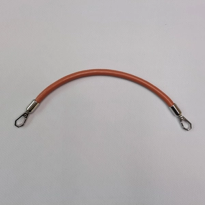 Detail of orange leather handbag strap with silver metal hooks on a white textured background