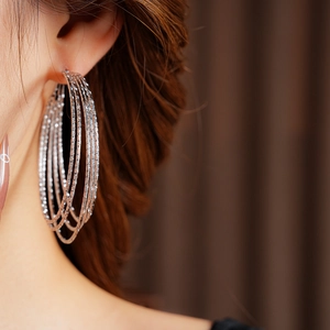 Close-up of stylish silver multi-layered hoop earrings worn on a female model