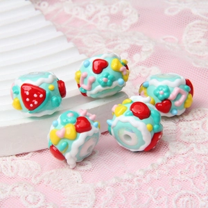 Macro detail of hand-painted beads with 3D strawberry, flower and heart patterns