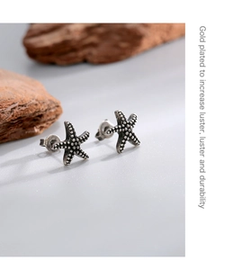 Macro detail of antique silver starfish stud earring with gold-plated finish and texture