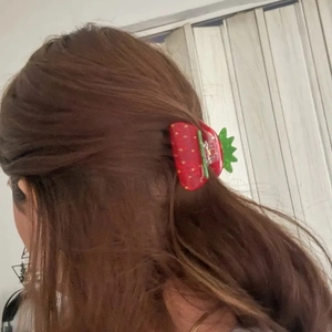 Sweet red acrylic strawberry hair claw clip shown on model for elegant hairstyling