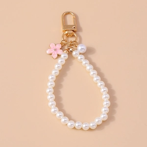 Detailed close-up of beaded pearl keychain with pink enamel flower charm and gold hardware