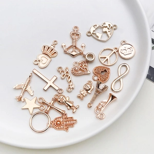 Assorted rose gold metal charms including heart and anchor shapes on a white ceramic plate