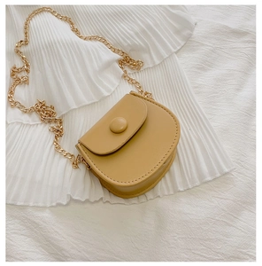 Détail d'un sac besace jaune moutarde avec bandoulière chaîne sur tissu plissé