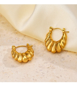 Detail of French vintage gold-plated C-shaped earrings with textured shell pattern