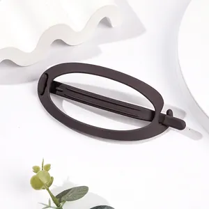 Close-up of matte dark brown oval hair claw clip with minimalist frosted texture finish