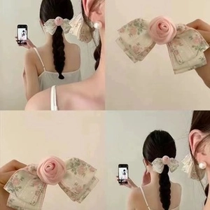 Detail of fabric hair clip with pink flower patterns and rose center on braided hair