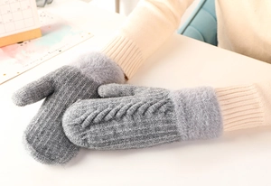 Detail of grey knitted mittens with soft faux fur cuffs and elegant cable knit texture