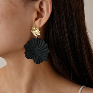 Detail of oversized black and gold floral earrings featuring matte textured petals
