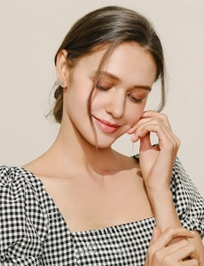 Close-up of turquoise hamsa stud earrings worn by a model in a black and white dress
